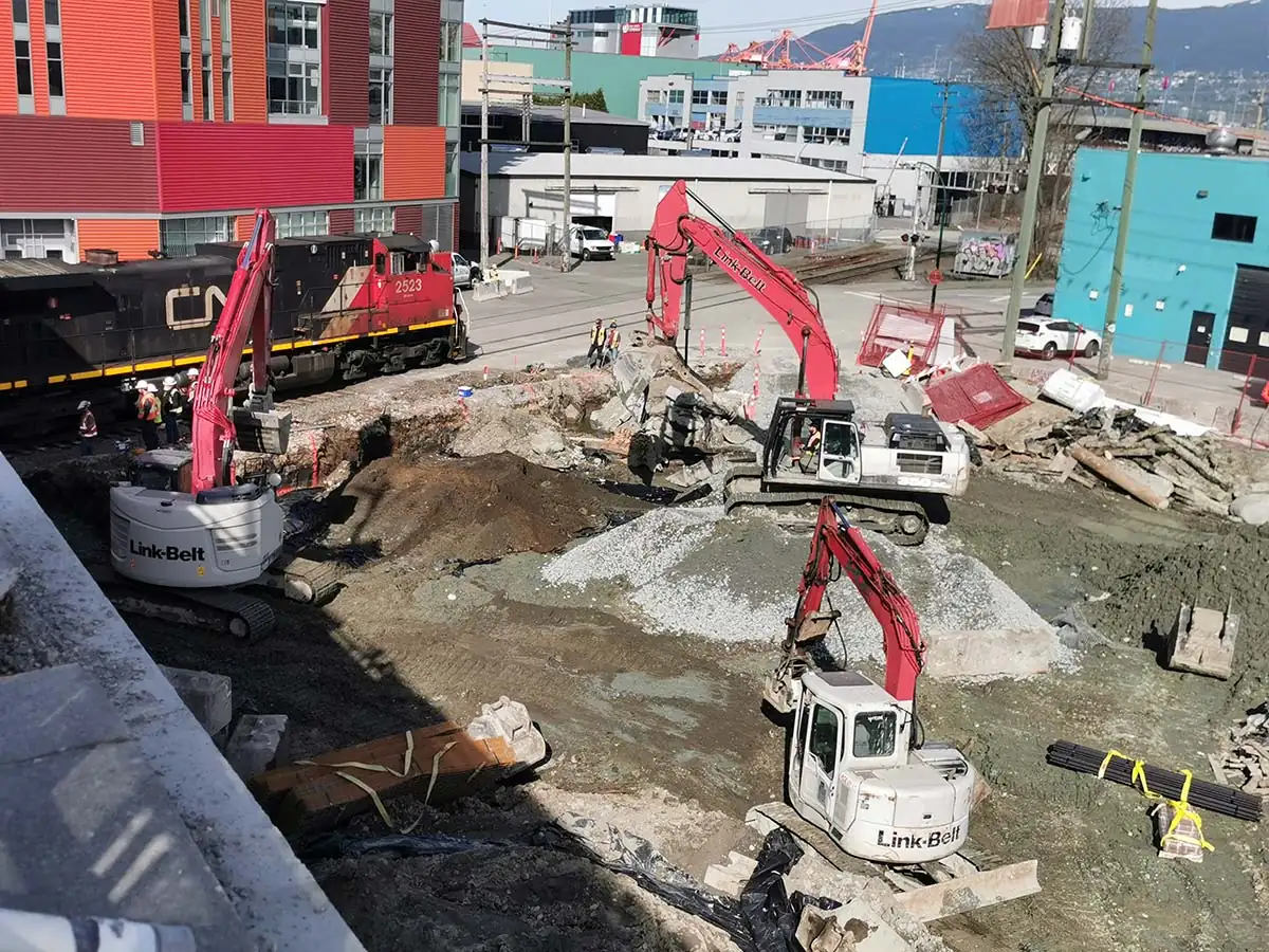 Excavation with a freight locomotive passing beside the site